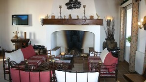 A cozy living room with a fireplace, a television, and a decorative wall. - Monte das Faias (Grandola)