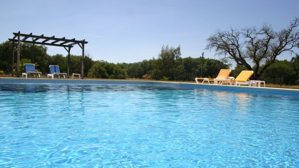 A clear swimming pool with blue water, surrounded by lounge chairs and a pergola. - Monte das Faias (Grandola)