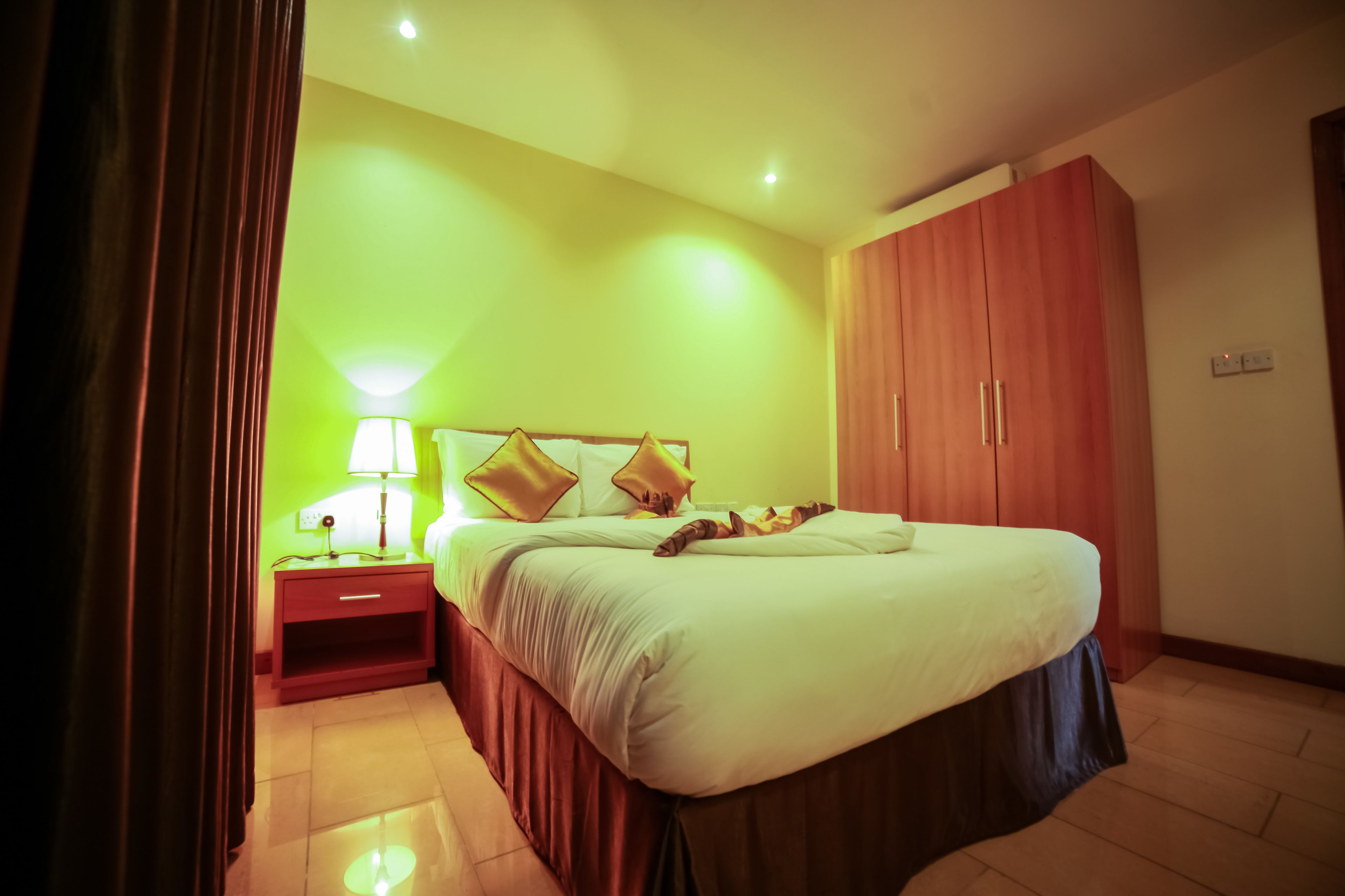 Un dormitorio con cama, mesita de noche, lámpara y armario.