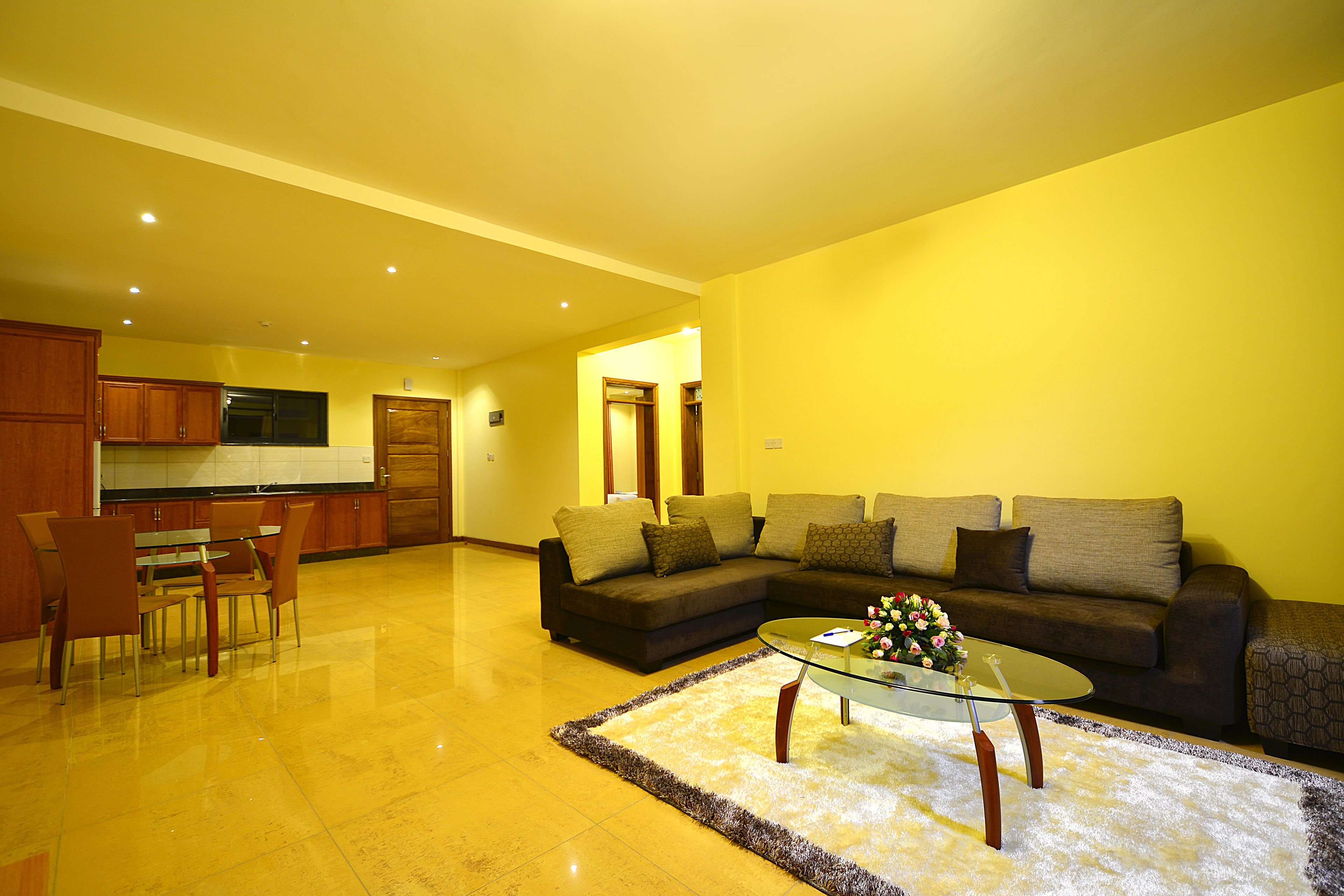 A living room with a glass coffee table, a sofa, and a dining area with chairs and a table.