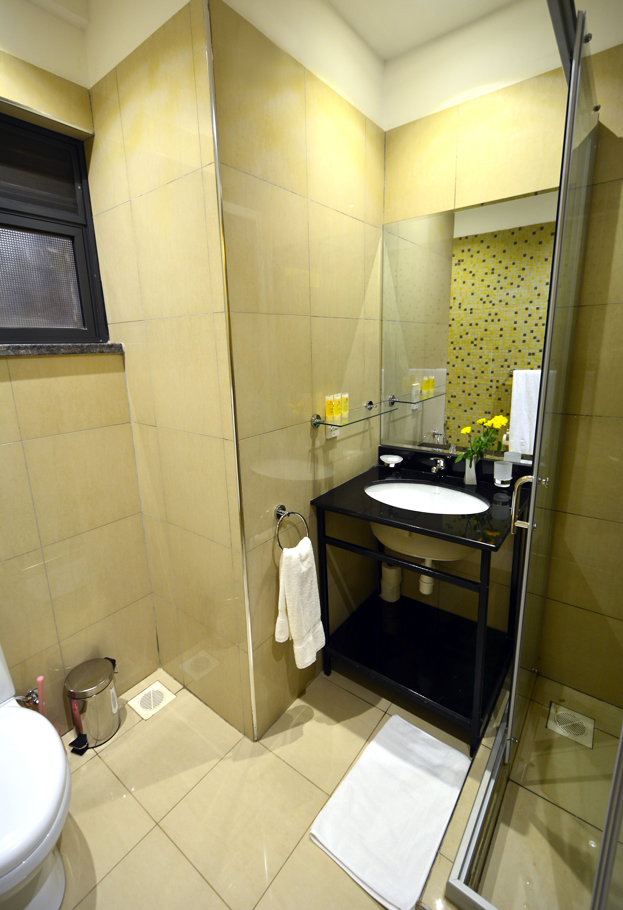 Een badkamer met een douchecabine van glas, een wastafel en een toilet.