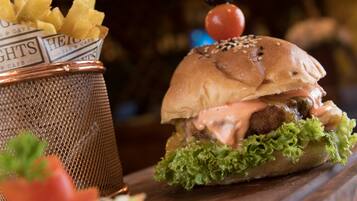 A burger with lettuce, a bun, and a sauce, alongside a basket of fries.
