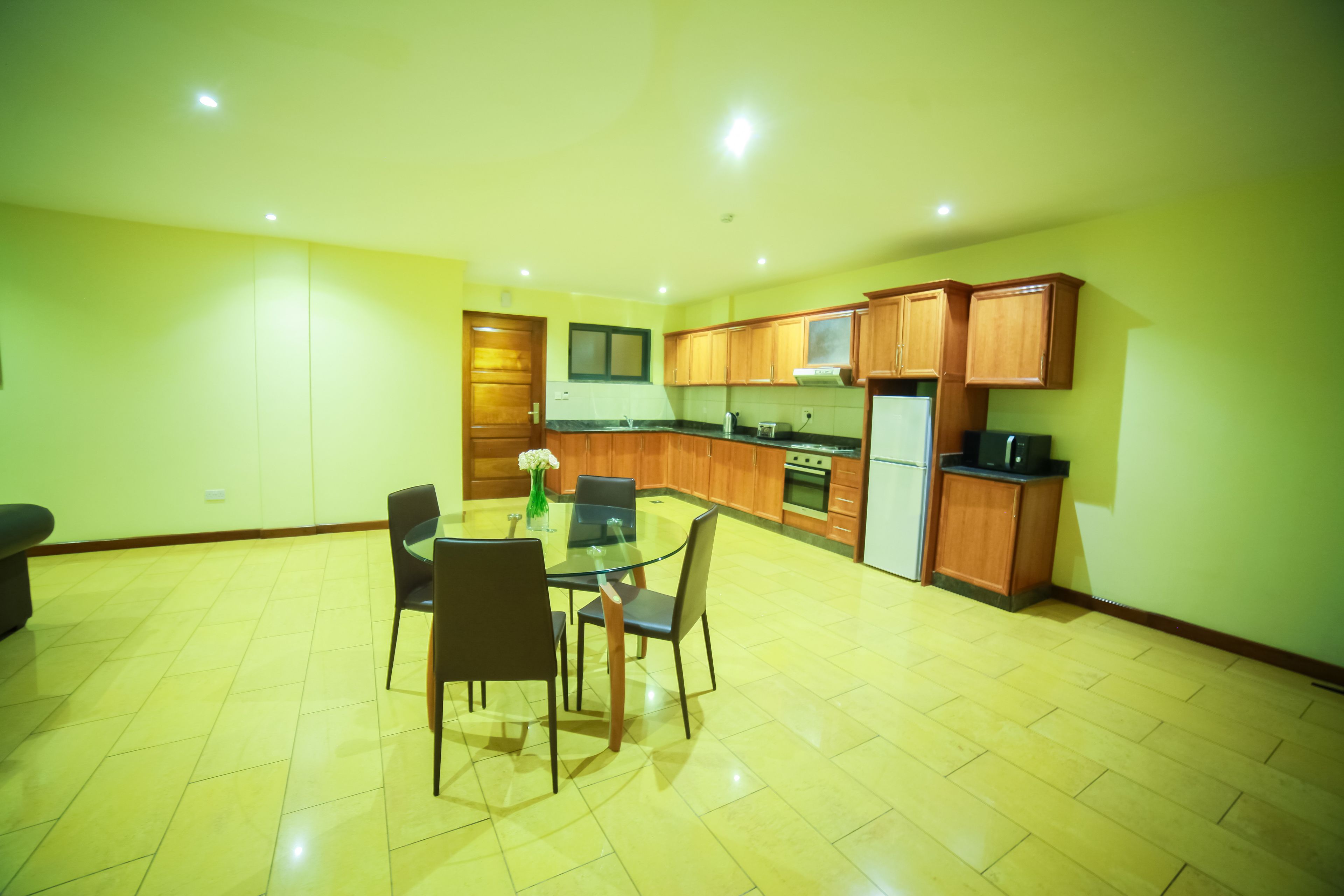 A spacious kitchen with wooden cabinets, a dining table with chairs, and a refrigerator.