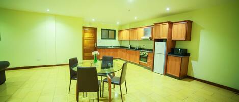 A spacious kitchen with wooden cabinets, a dining table with chairs, and a refrigerator.