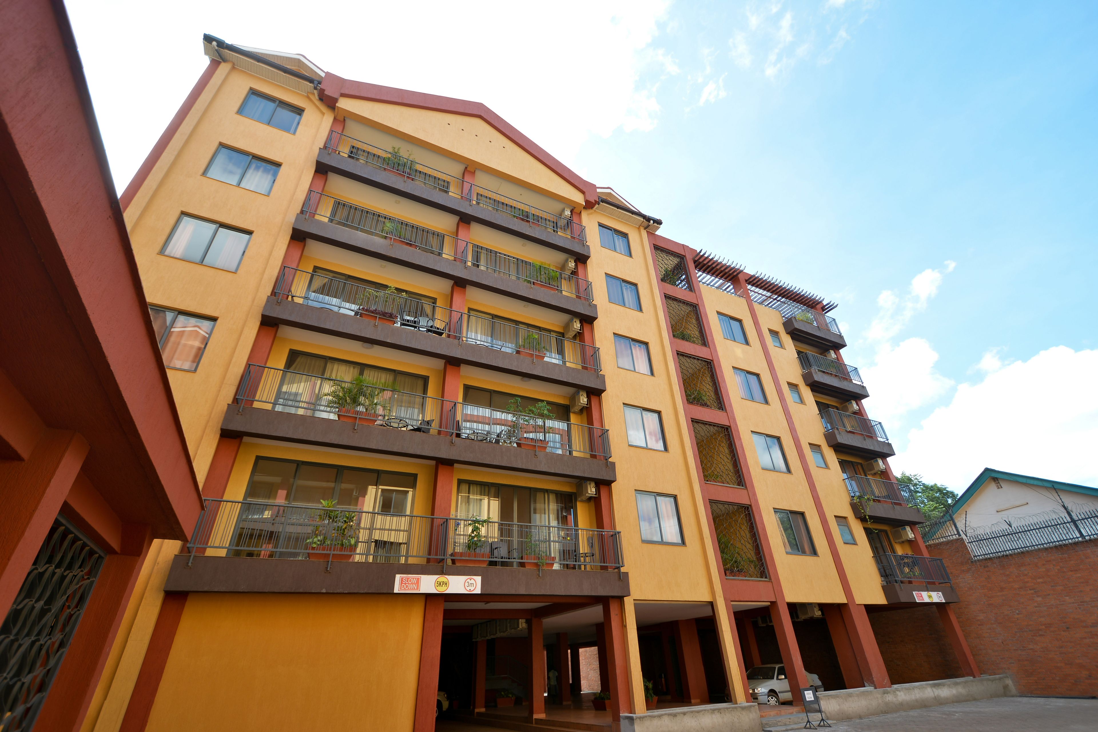 A multi-story building with balconies, a sign indicating a 5-star rating, and a clear sky.