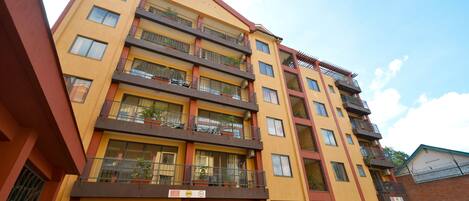 A multi-story building with balconies, a sign indicating a 5-star rating, and a clear sky.