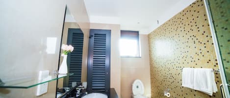 Un baño moderno con repisa de vidrio, lavabo negro, inodoro y zona de ducha.