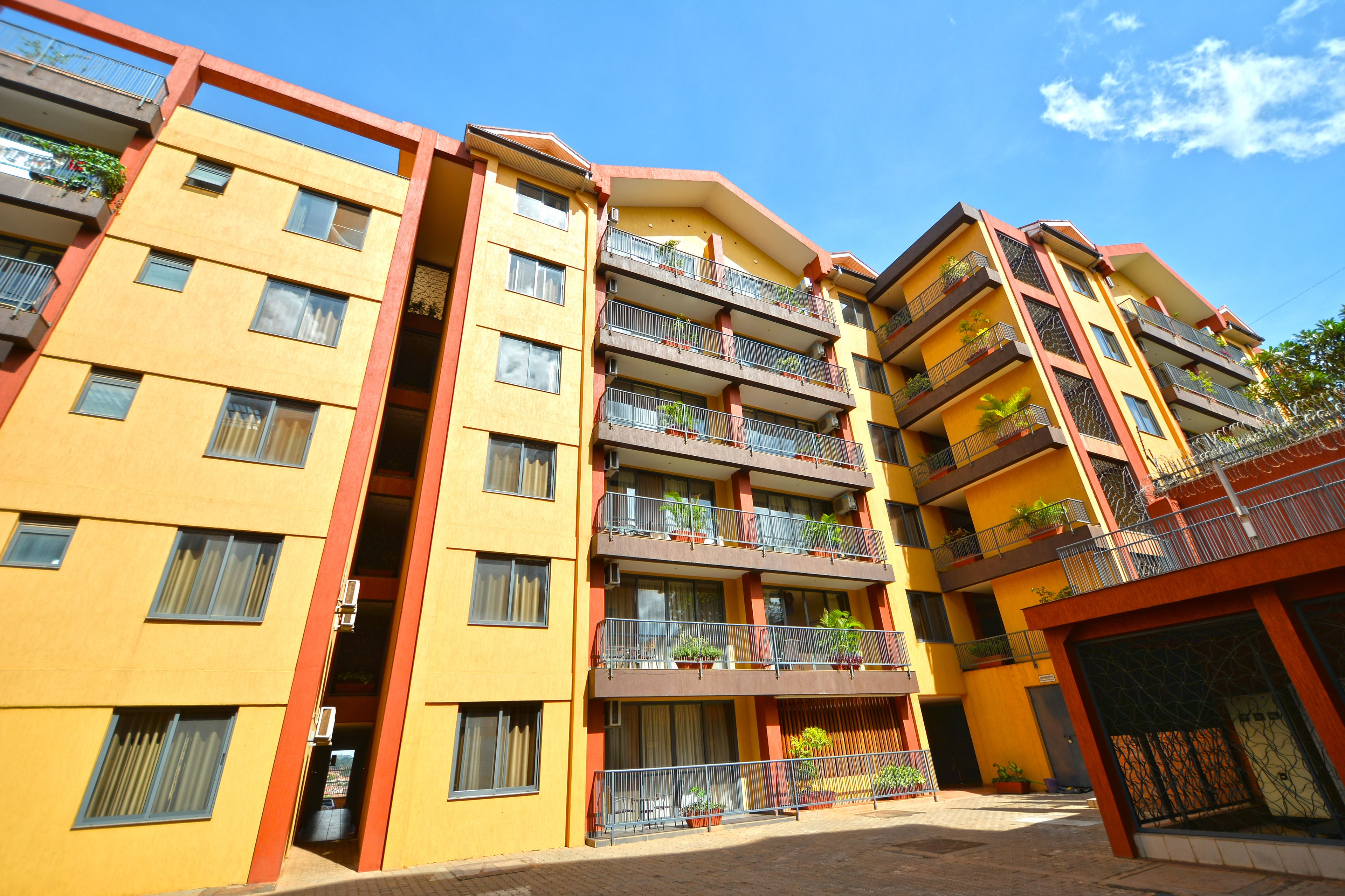 A multi-story residential building with balconies, windows, and potted plants.