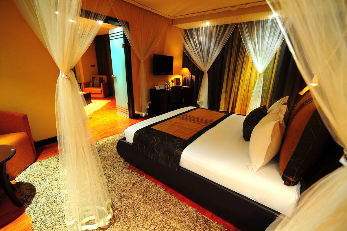 Una habitación de hotel con una cama grande, un escritorio, una silla y un televisor en la pared.