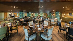 Un restaurante amplio con múltiples mesas y sillas, techo de madera y vistas al exterior.