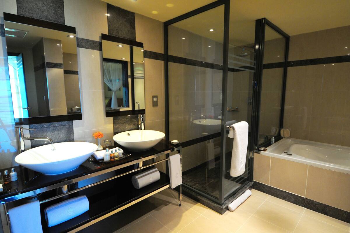 Un baño moderno con un lavamanos grande, una bañera y una ducha con mampara de vidrio.