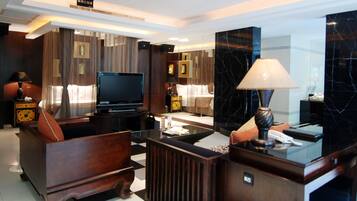 Una habitación de hotel moderna con televisión de pantalla plana, muebles de madera y detalles de mármol.