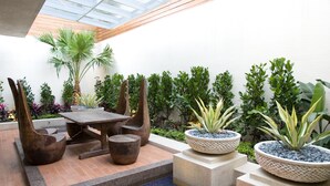 An outdoor patio with a wooden table and chairs, surrounded by various potted plants and a palm tree. - Yes Motel City Resort Paradise (New Taipei City)