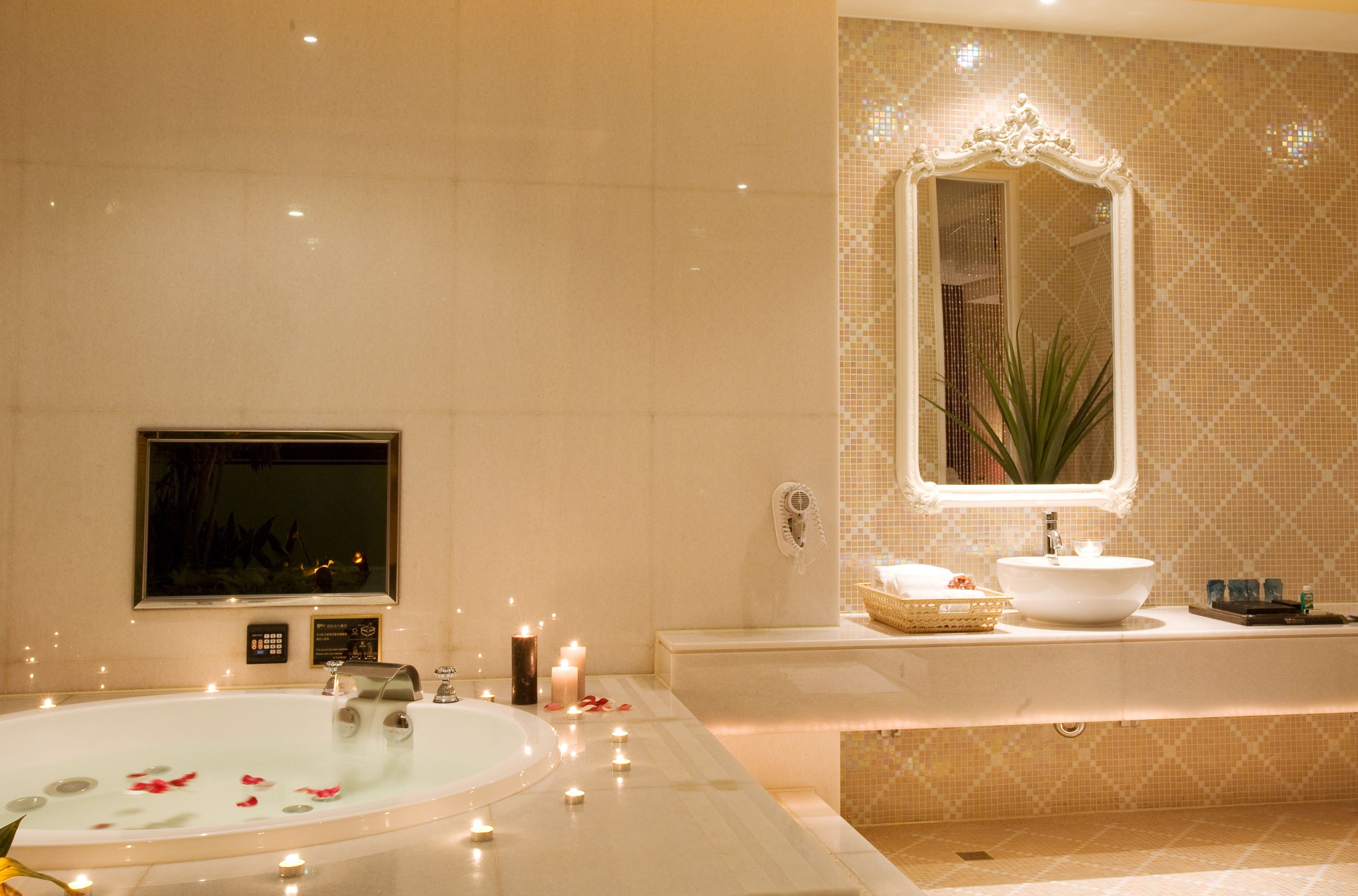 A bathroom with a bathtub, a sink, a mirror, and a wall-mounted TV.