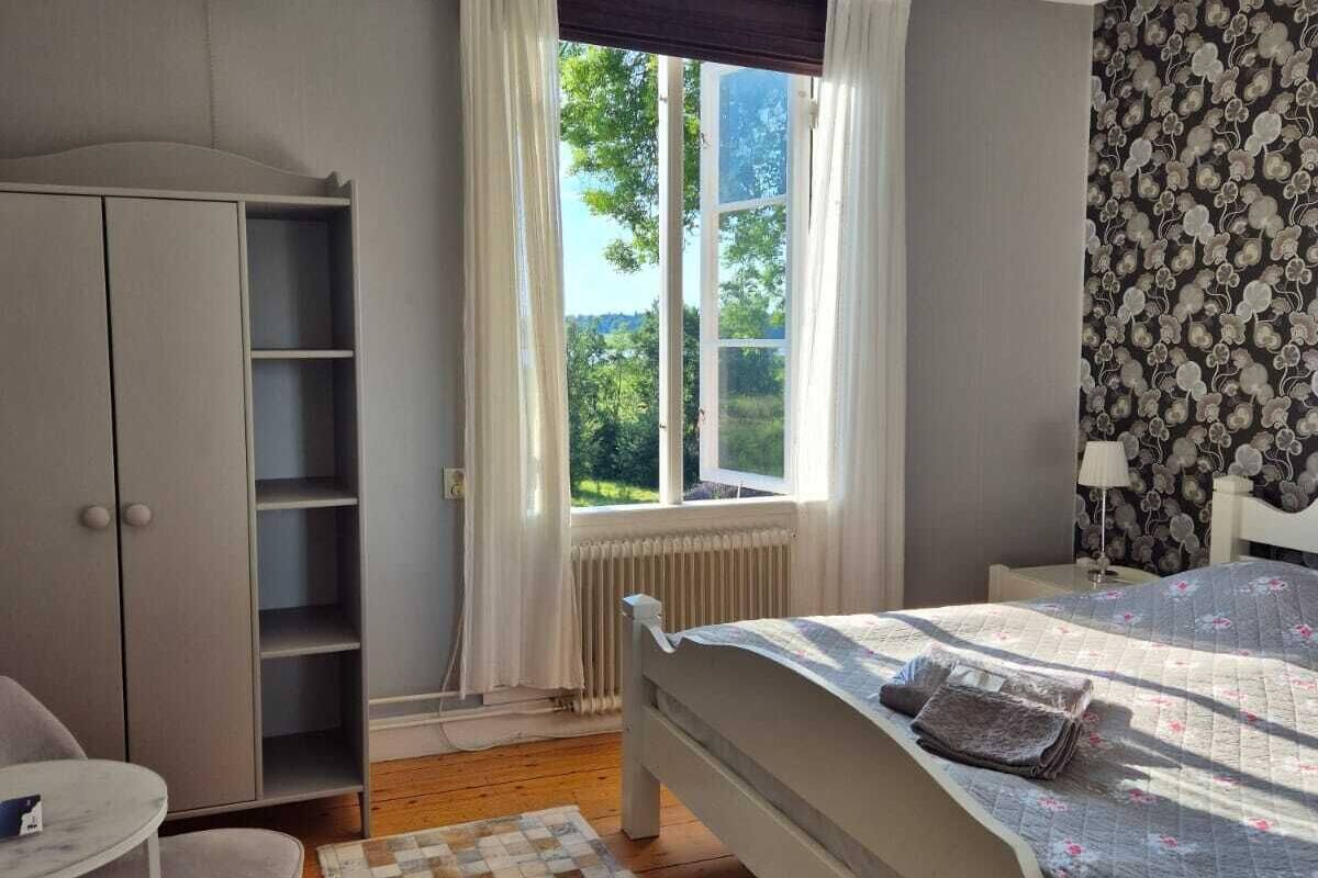 Une chambre à coucher avec un lit, une armoire, un bureau et une fenêtre avec des rideaux.