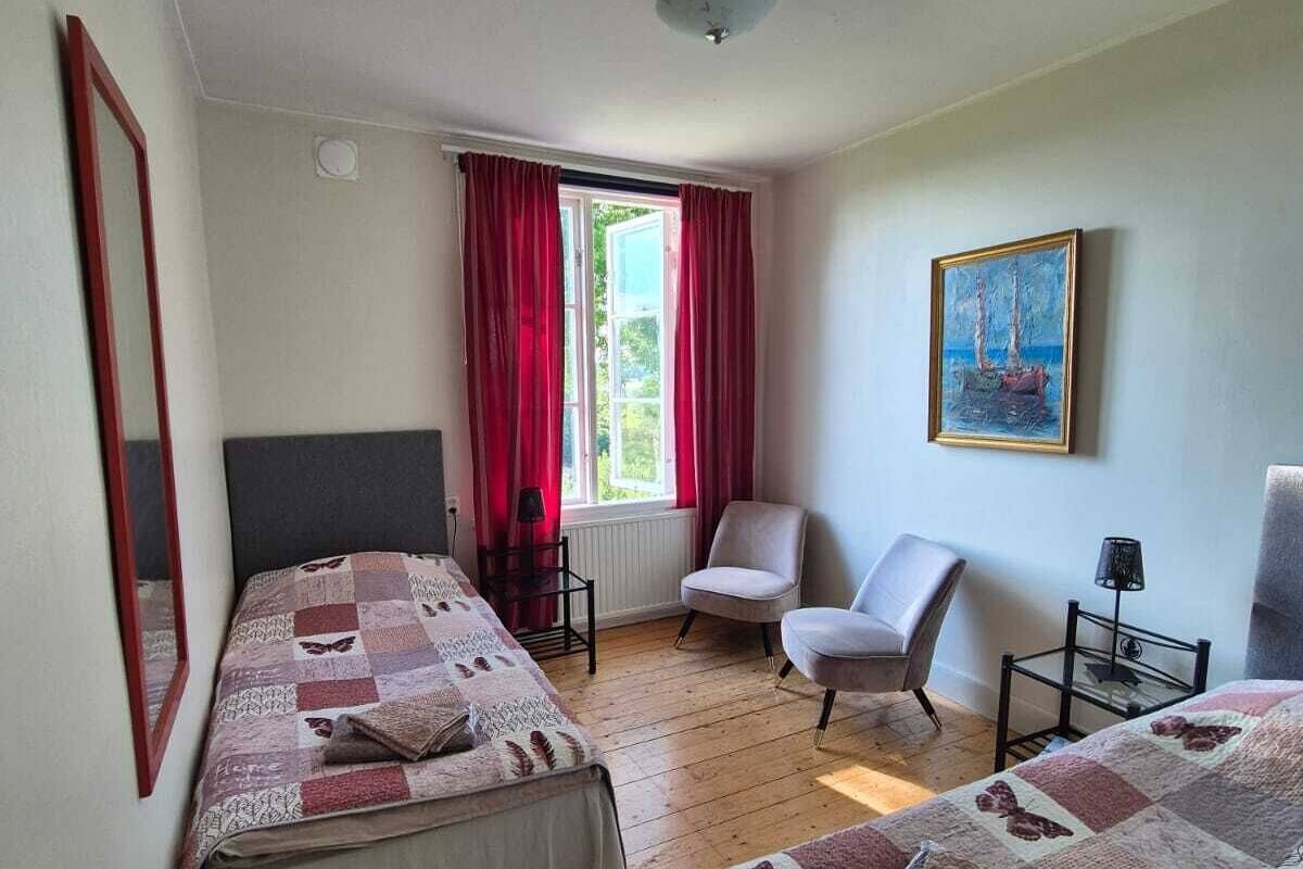 Une chambre avec deux lits, une chaise, une table et un tableau au mur.