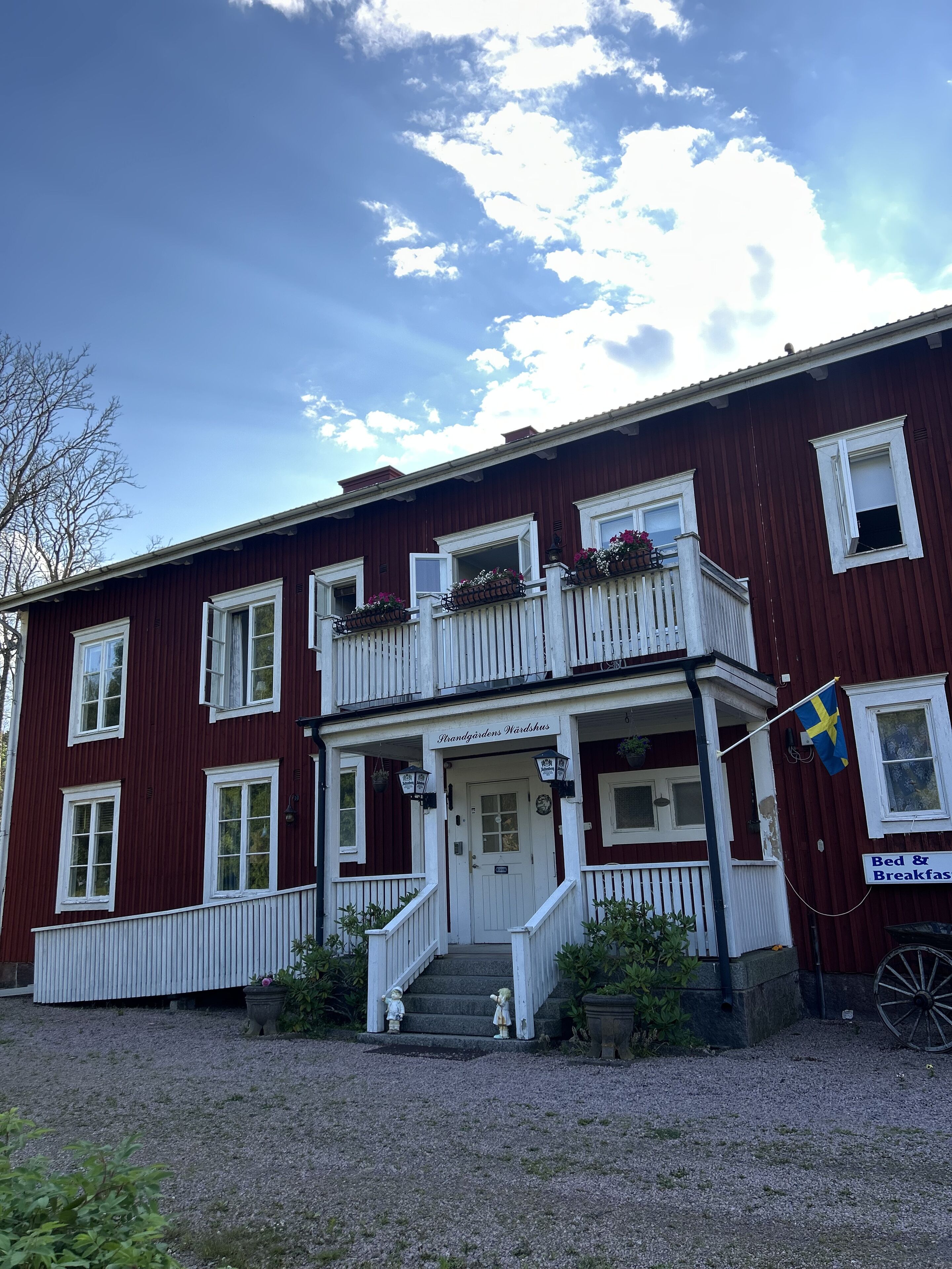 A two-story building with a white porch and a flag.