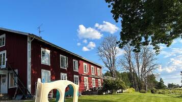 Un parque infantil con un tobogán frente a un edificio rojo con varias ventanas y una escalera.
