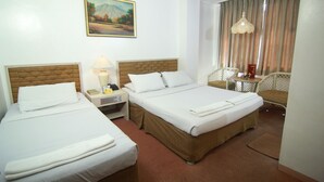 A hotel room with two beds, a desk, a chair, a lamp, and a painting on the wall. - Hotel Supreme (Baguio)