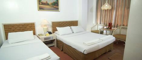 Habitación de hotel con dos camas, un escritorio, una silla, una lámpara y un cuadro en la pared.