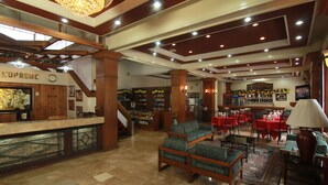 A spacious lobby with a reception desk, seating area, and a staircase leading to upper floors. - Hotel Supreme (Baguio)