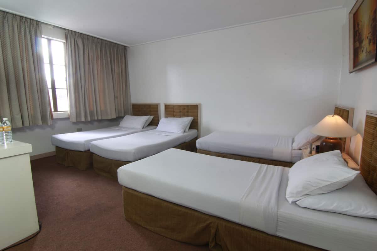 A hotel room with two single beds, a desk, and a lamp.
