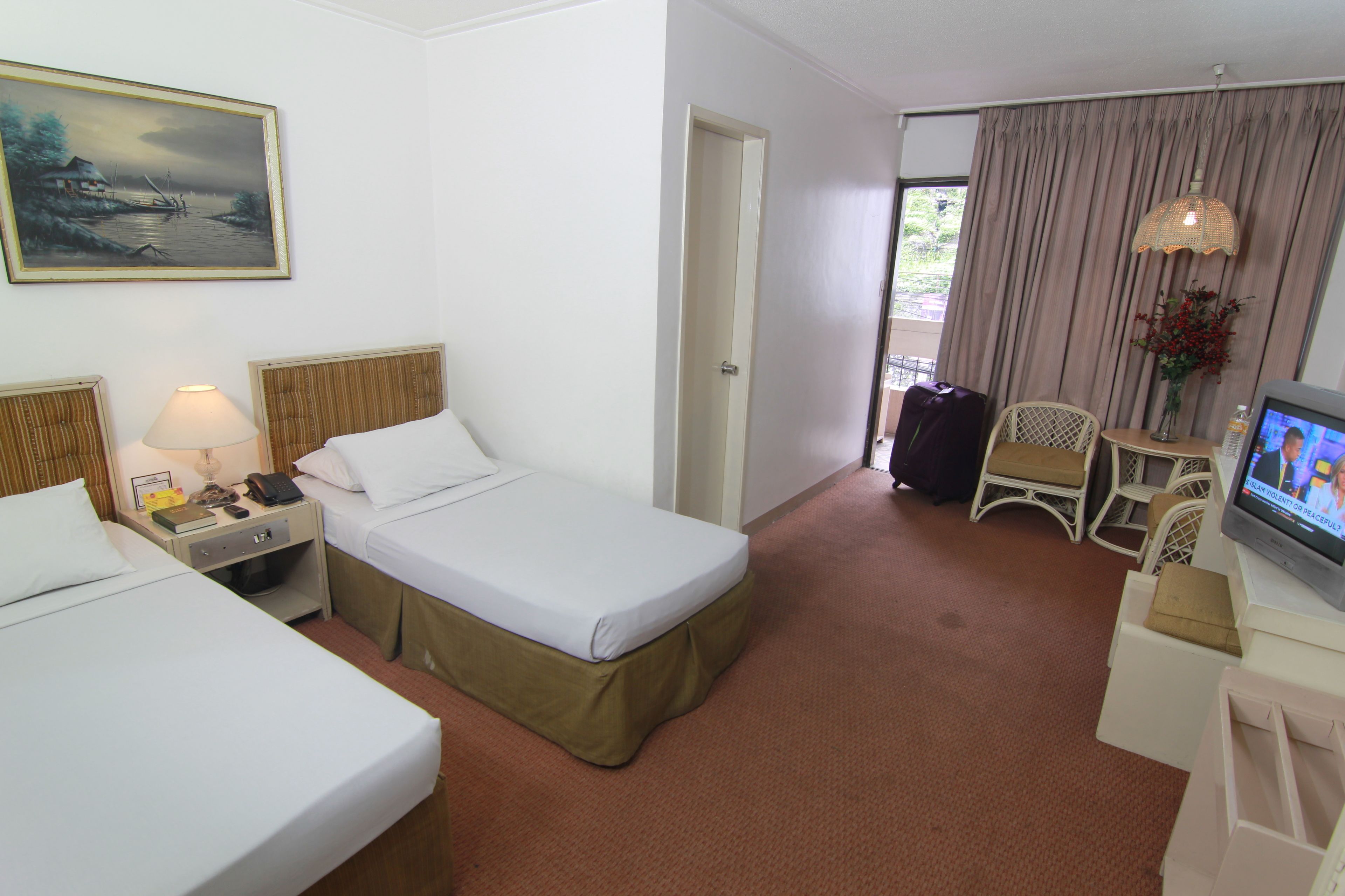 Una habitación de hotel con dos camas, un escritorio con lámpara, televisión y una silla.