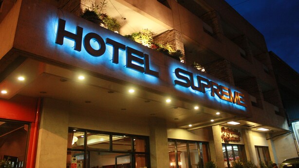 A hotel named "HOTEL SUPREME" with illuminated signage, large windows, and a modern architectural design. - Hotel Supreme (Baguio)