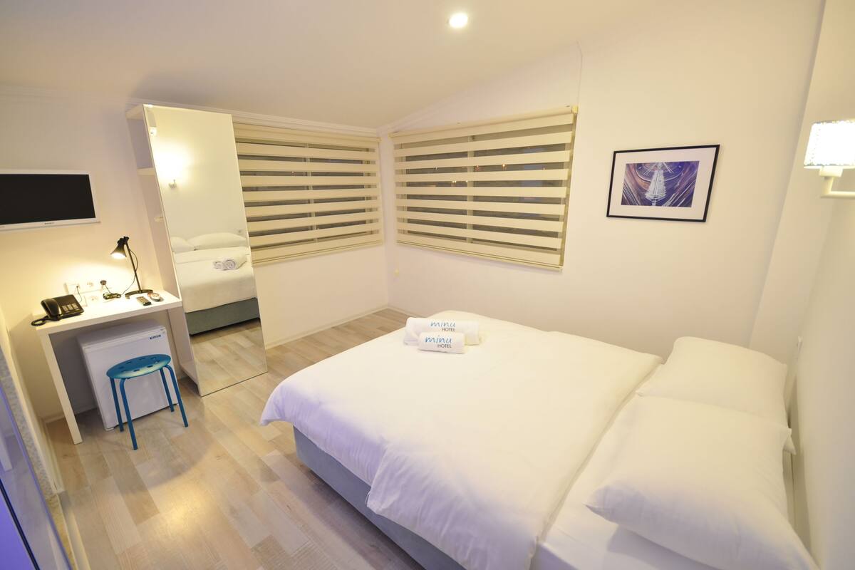 Una habitación de hotel con una cama, un escritorio y una silla.