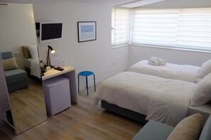 Una habitación moderna y bien iluminada con cama, escritorio y zona de estar.