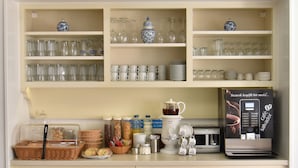 Una kitchenette con cafetera, armarios de almacenamiento y refrigerador.