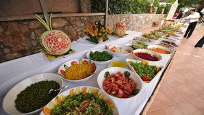 Une table de buffet garnie de divers plats et une pastèque sculptée en forme de fleur.