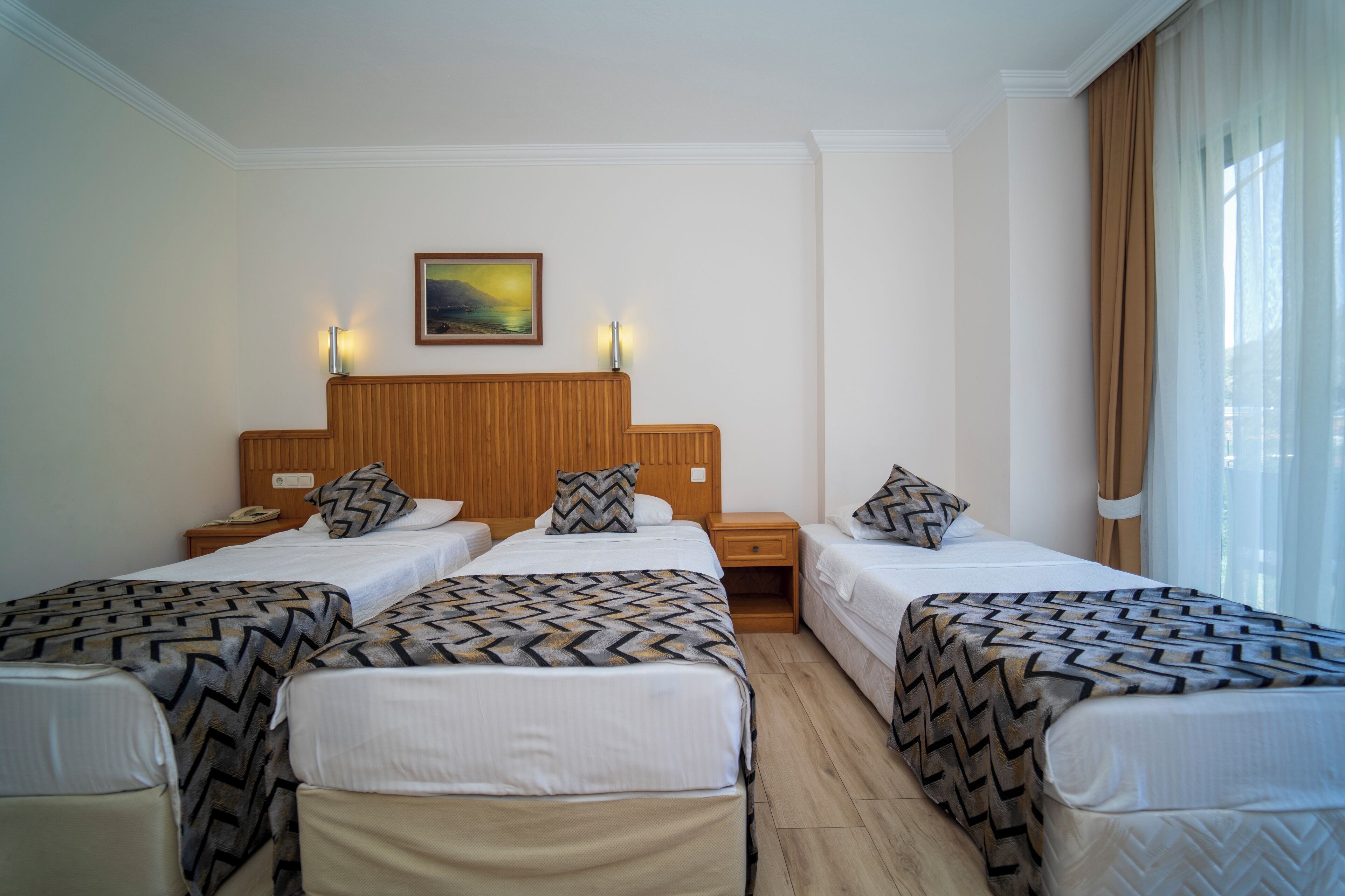 Ein Hotelzimmer mit zwei Einzelbetten, einem Holzkopfteil, einem Nachttisch mit Telefon und einem Bild an der Wand.