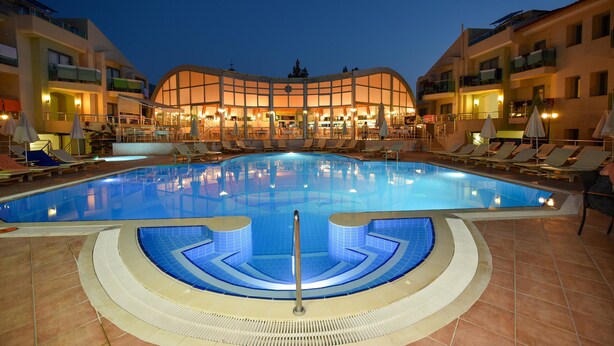 Une piscine avec des chaises longues et, au fond, un bâtiment doté de balcons.