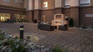 A courtyard with outdoor seating, a fireplace, and a building with multiple windows. - Hampton Inn & Suites Reno West (Reno)