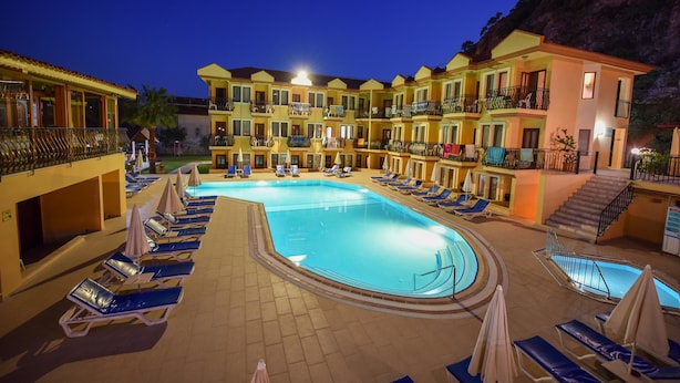 Un hotel con piscina, varios balcones y zonas de descanso.