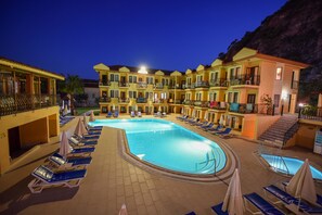 Un hotel con piscina, varios balcones y zonas de descanso.