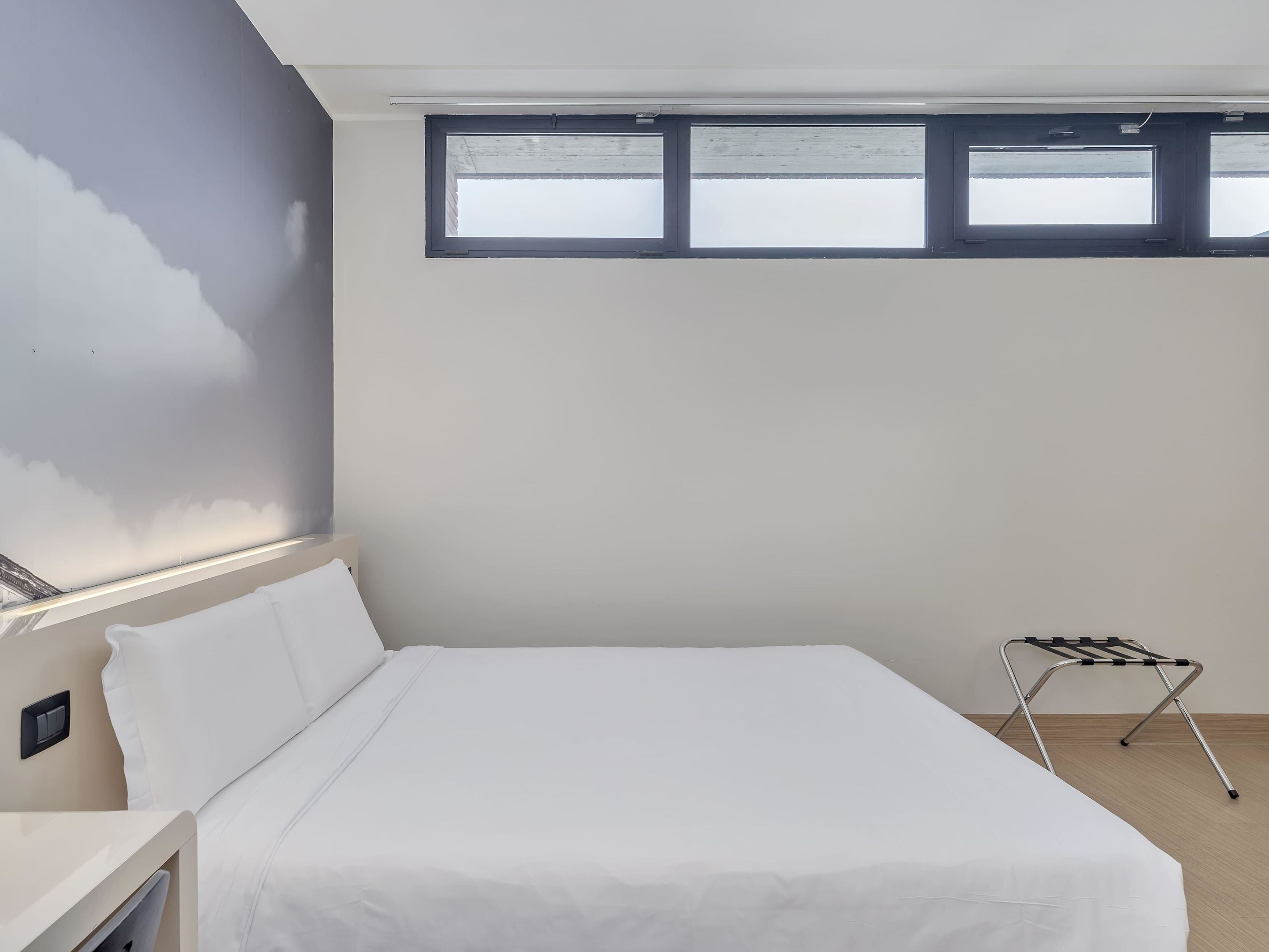 Una camera da letto con un letto, un comodino, una finestra e un termosifone.