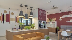 Ein modernes Café mit einer zentralen Theke, Sitzbereich und einer Kaffeemaschine.