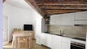 A compact kitchen with white cabinets, a wooden dining table, and a built-in oven. - Residence La Pineta (Budoni)