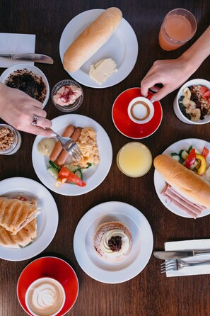 A table with various dishes including sausages, bread, and a dessert. - OREA Resort Devět Skal Vysočina (Snezne)