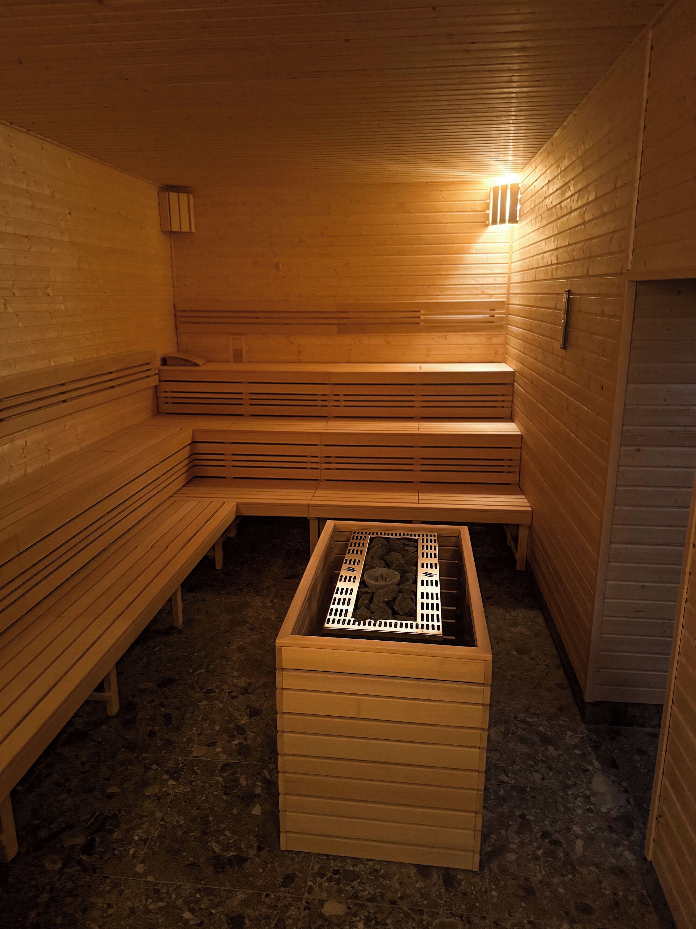 A sauna with wooden benches and a central heating unit.