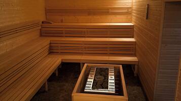 A sauna with wooden benches and a central heating unit.