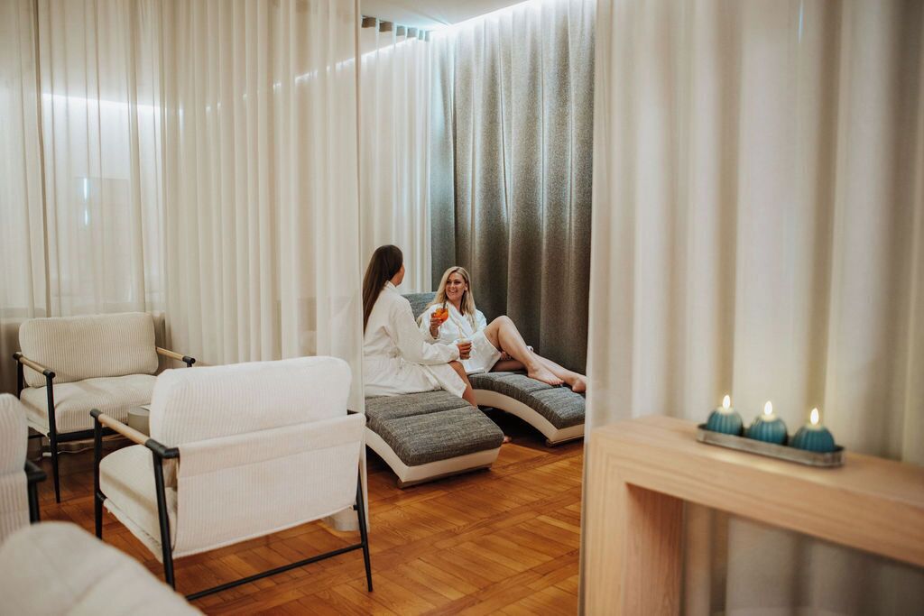 Un cuarto de spa con dos sillones de masaje, piso de madera y una mesita de madera con velas.