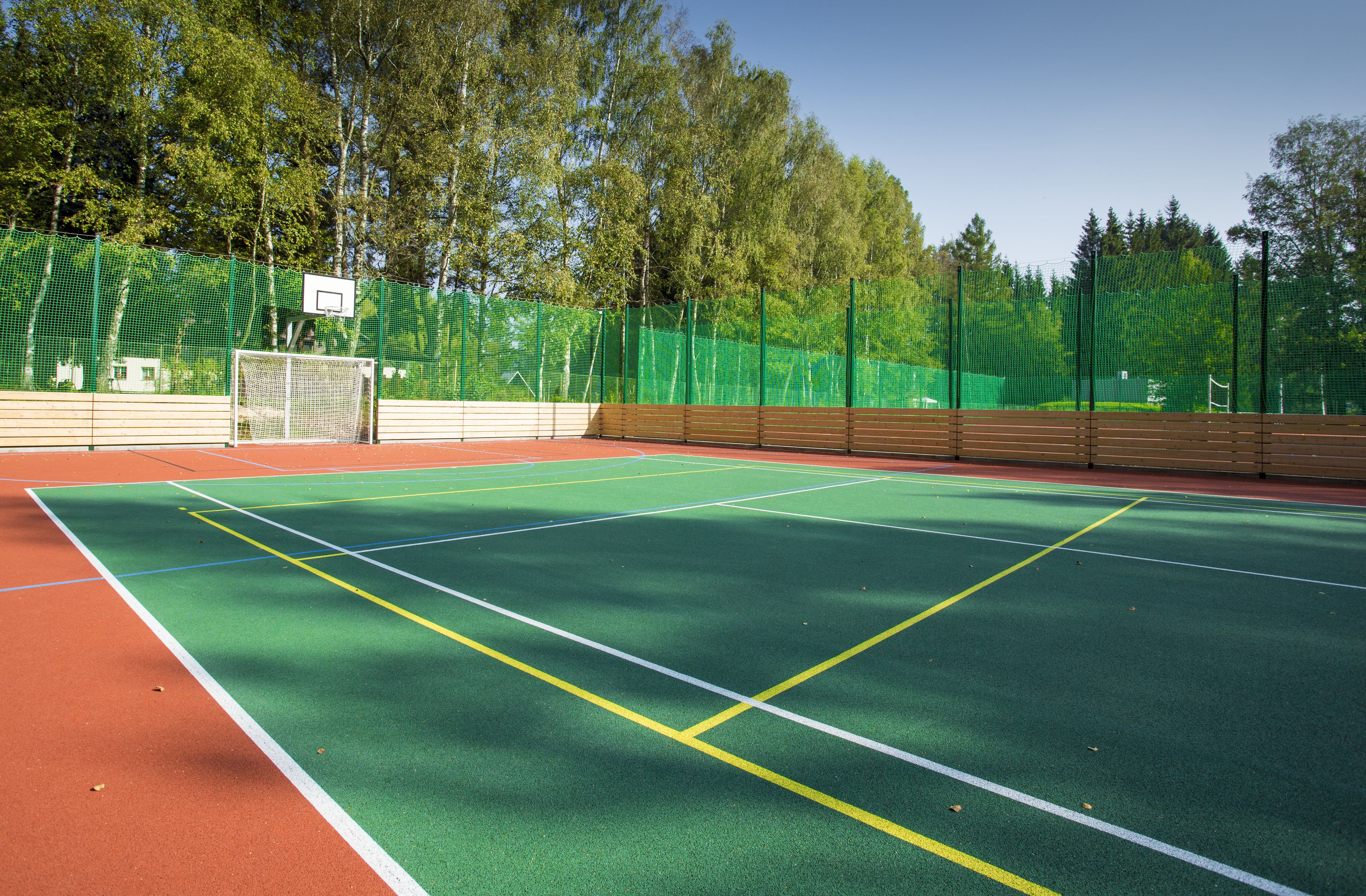 A tennis court with a green playing surface, white boundary lines, and a net.