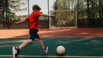 Una cancha de tenis con red, valla y árboles al fondo.