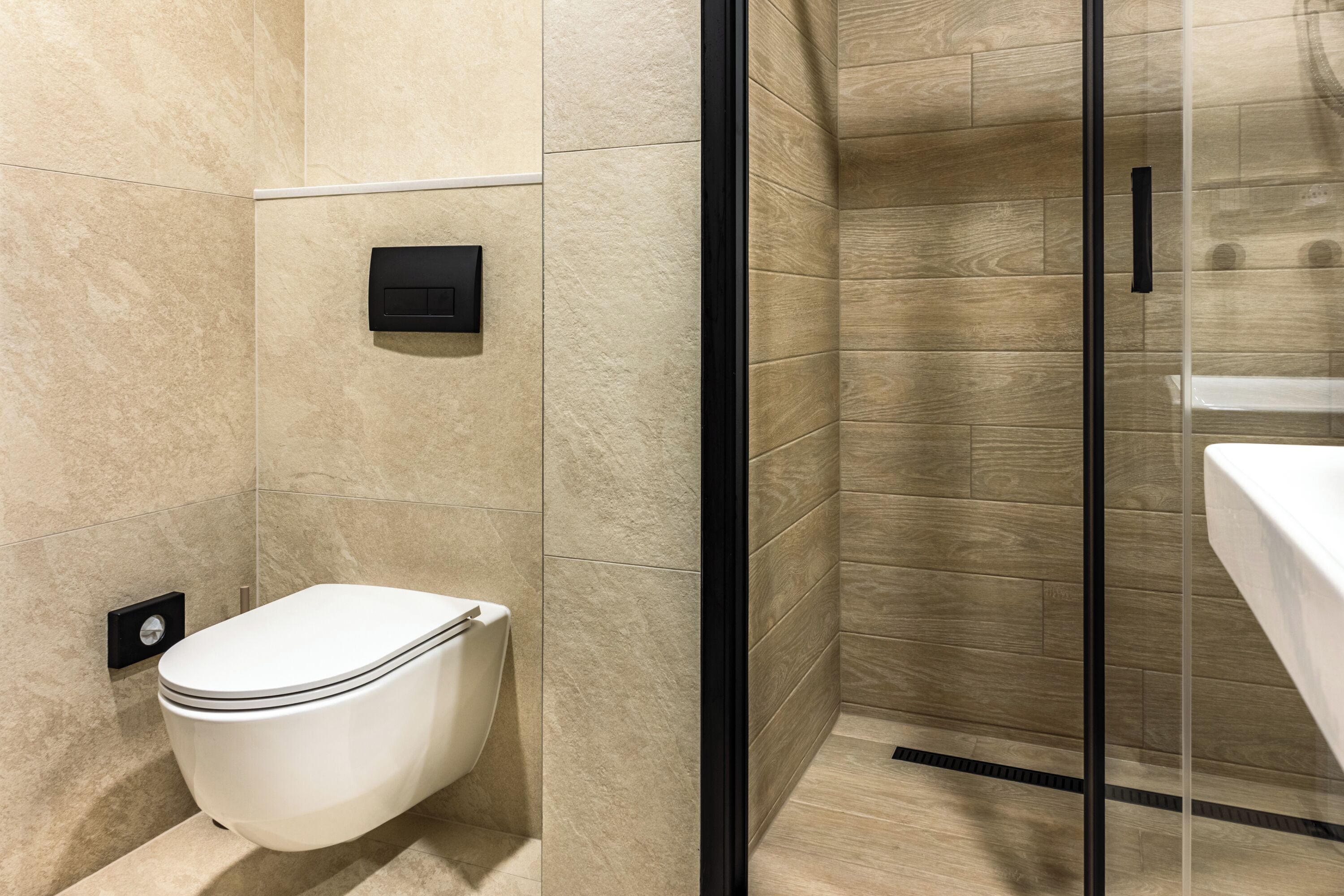 Un baño moderno con inodoro, cabina de ducha de vidrio y lavamanos.