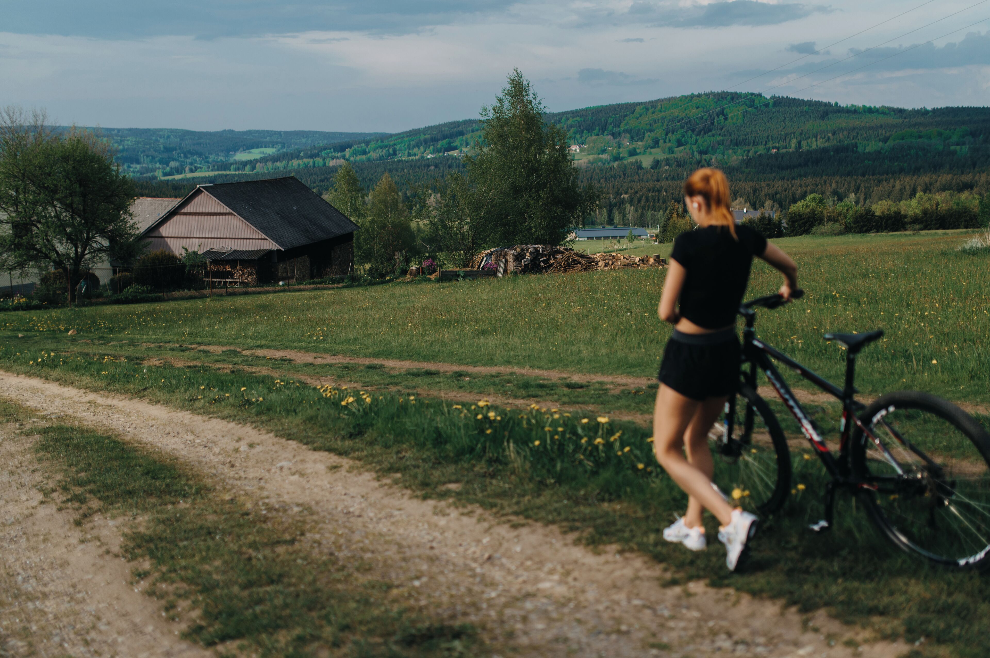 A rural landscape with a dirt path, a bicycle, and a building in the background.