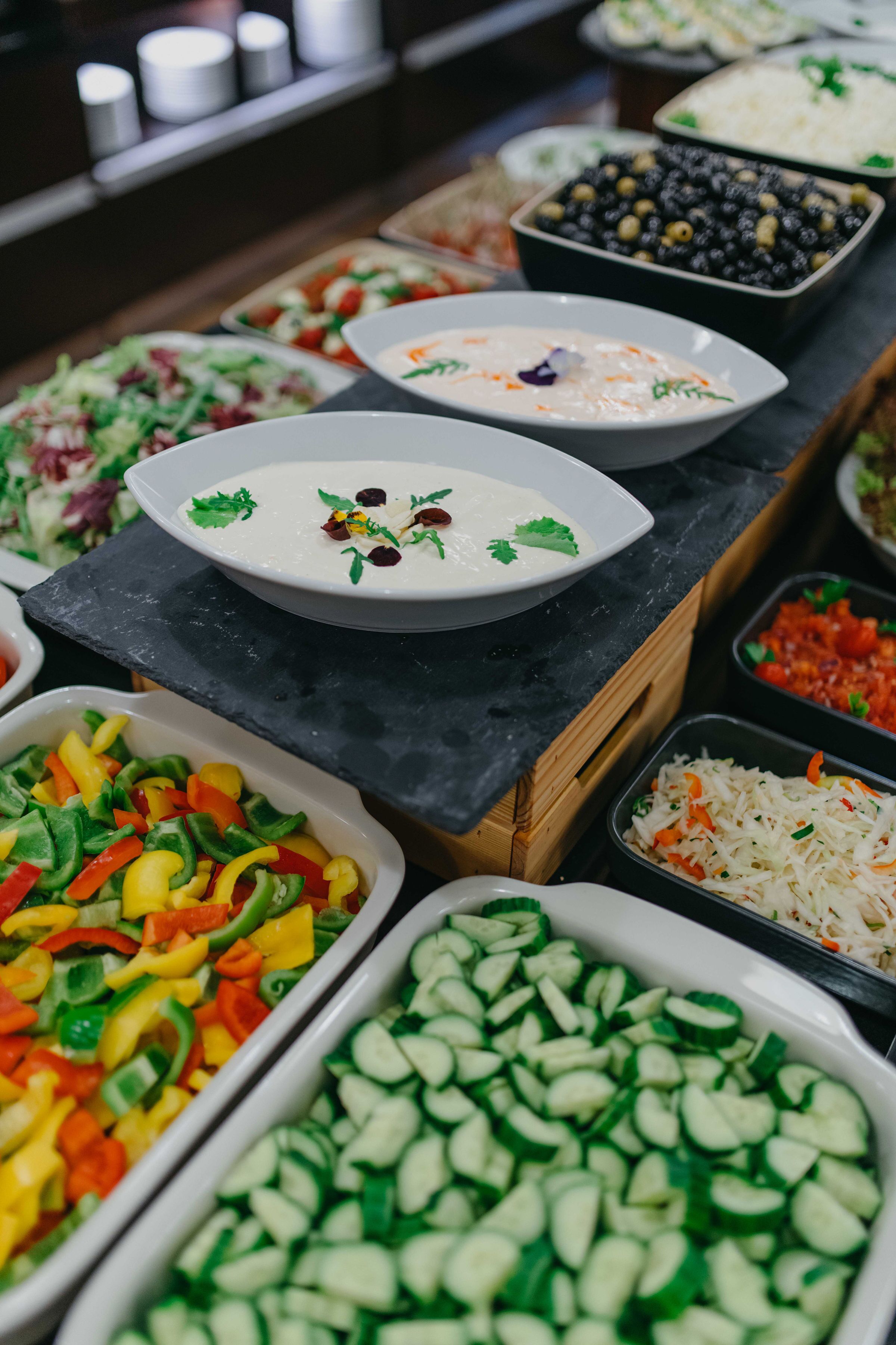 Un bufé con diversos platos, incluyendo ensaladas, arroz y verduras cortadas.