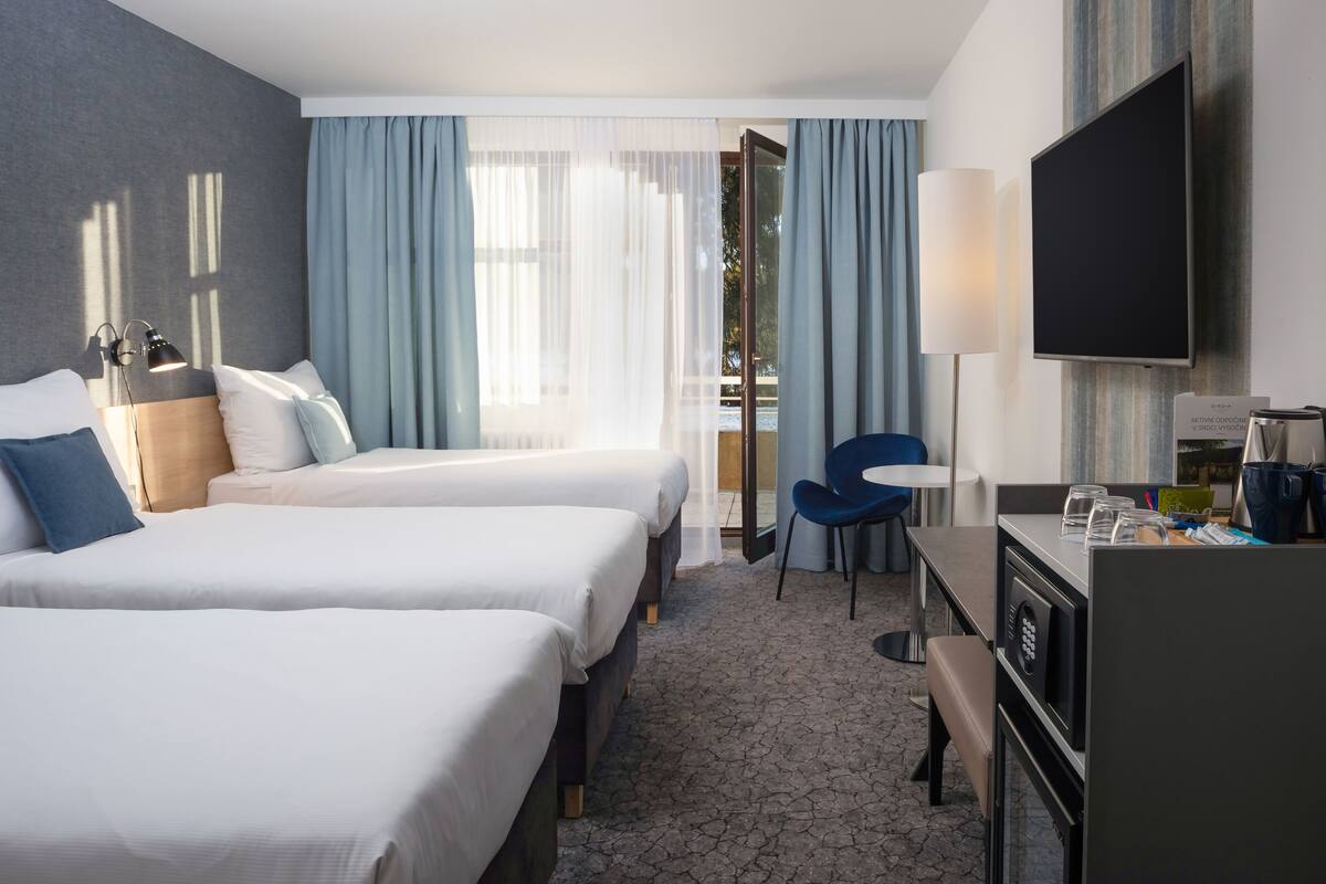A hotel room with two beds, a desk with a TV, and a chair.